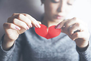 Young woman showing red ripped paper heart