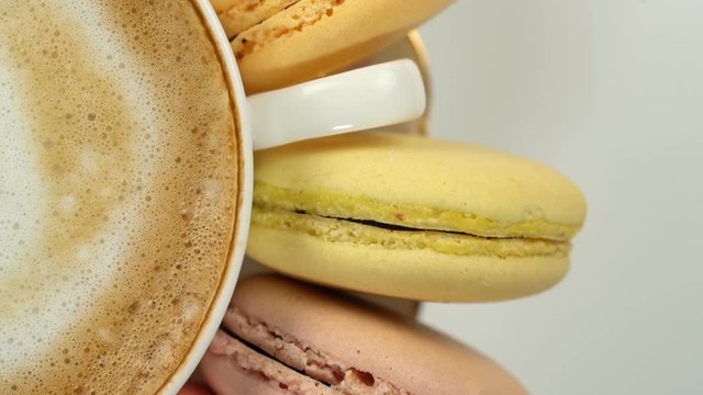 Pastel macarons around a coffee cup