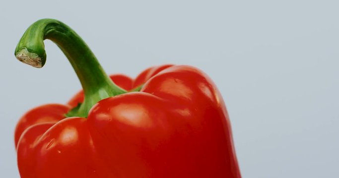 Red pepper rolling on the white wall background. Macro shooting. Close up