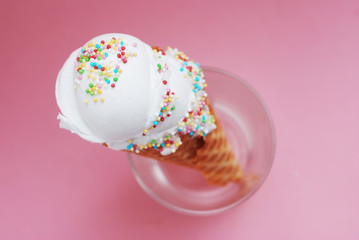 Ice Cream cone with scoop of Vanilla ice cream and Confetti in glass isolated on Pink background. top view. Party, dessert, summer concept.