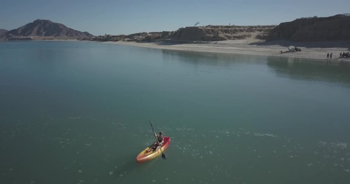 Aerial camera flies over two kayakers in the water turning around.
