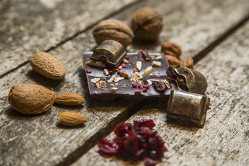 Pieces of black, chocolate with cranberry , nuts and almond  on wood background