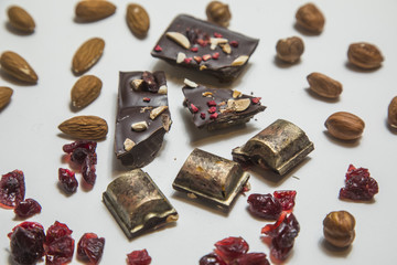 Pieces of black, chocolate with cranberry , nuts and almond  on white background.