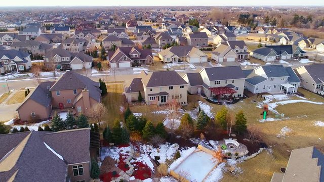 Beautiful neighborhoods as Winter melts into Spring, homes with snow and ice, aerial view.
