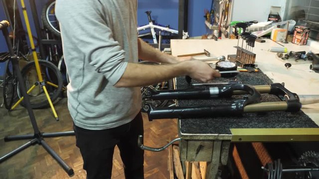 The mechanic unscrews the metal pin assembles a bike in his workshop.