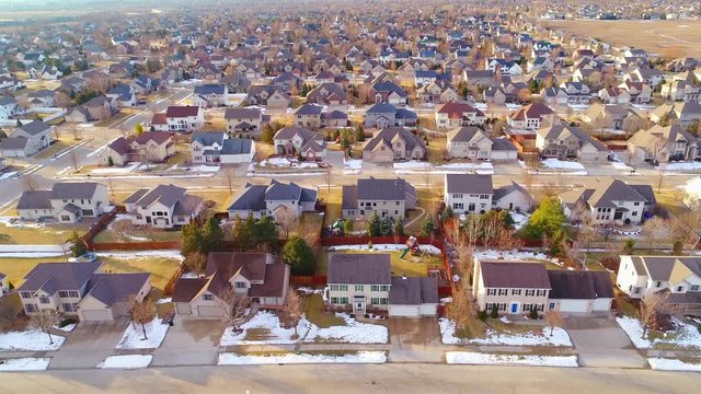Beautiful neighborhoods as Winter melts into Spring, homes with snow and ice, aerial view.
