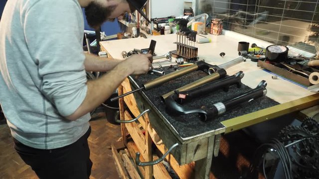 The mechanic uses a hammer to repair a bicycle
