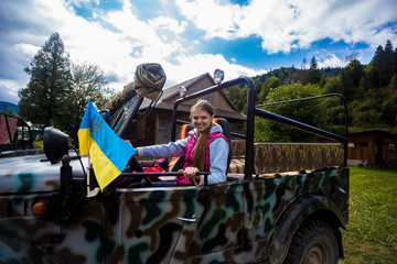 Happy young tourist woman travel by car in mountain forest in autumn with dramatic sky on background