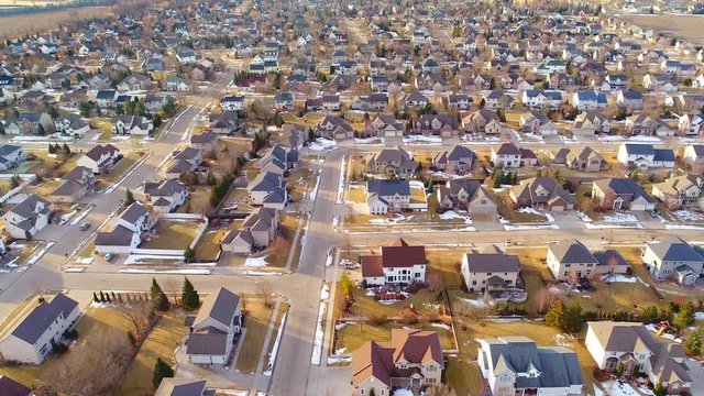 Beautiful neighborhoods as Winter melts into Spring, homes with snow and ice, aerial view.
