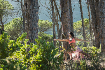 Naklejka na ściany i meble Woman doing yoga in a forest dancing with a Mountain in the background.