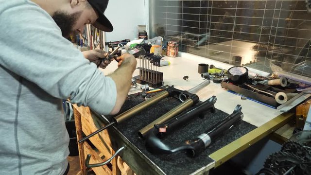The mechanic uses a hammer to repair a bicycle