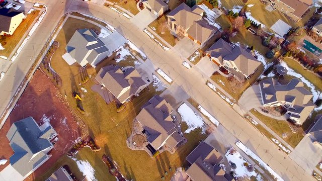 Beautiful neighborhoods as Winter melts into Spring, homes with snow and ice, aerial view.
