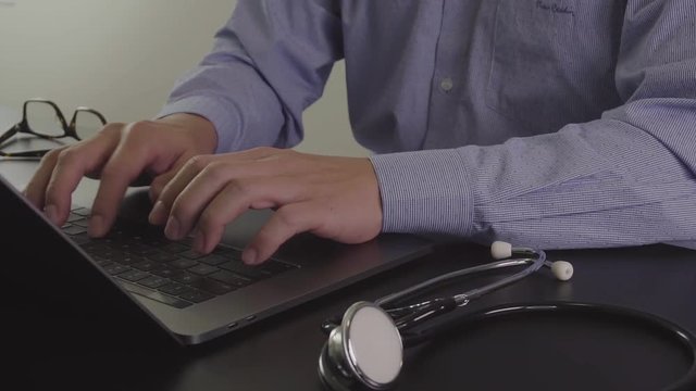 Smart doctor working with new modern laptop computer for online consult in hospital in slow motion

