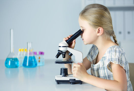 Schoolgirl looking through microscope in science class