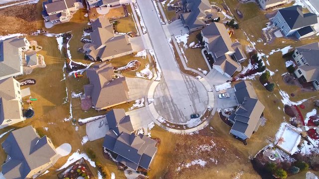 Beautiful neighborhoods as Winter melts into Spring, homes with snow and ice, aerial view.
