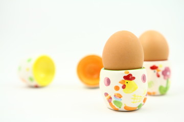 Wielkanoc - śniadanie - jajka na kolorowych podstawkach - białe tło - obrazy, fototapety, plakaty