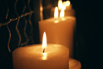 Burning candles in darkness, closeup