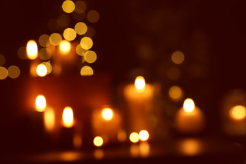 Blurred view of beautiful burning candles in darkness