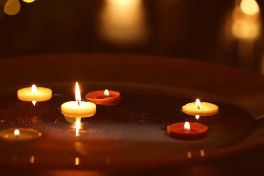 Small burning candles floating in plate with water