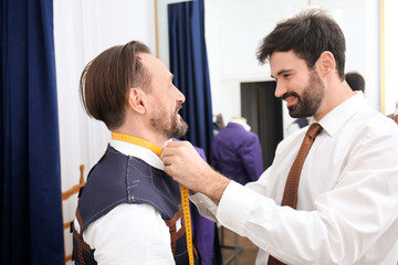 Tailor measuring client for custom made suit in atelier