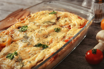 Glass baking dish with delicious casserole on table, closeup. Fresh from oven