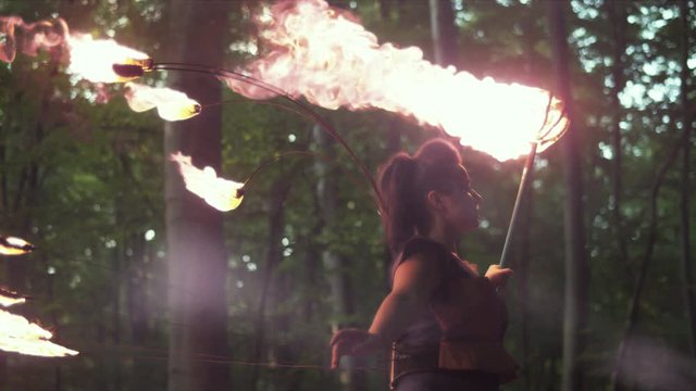 Female artist with fire staff in the wood