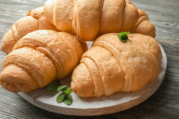 Delicious croissants on wooden board, closeup