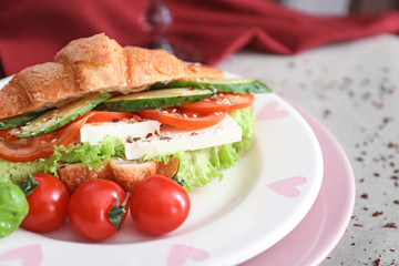 Plate with tasty croissant sandwich on table