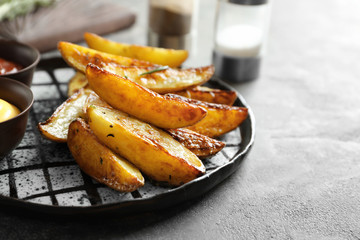 Plate with tasty potato wedges on table