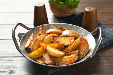 Dish with tasty potato wedges on table