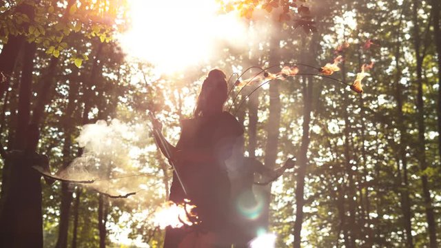 Contre jour of a female artist with fire staffs