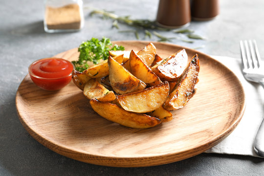 Plate with tasty potato wedges and tomato sauce on table