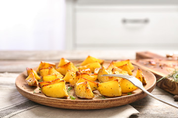 Dish with delicious oven baked potatoes on table