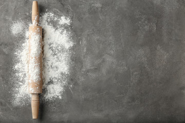 Scattered flour and rolling pin on grey table