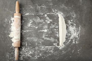 Scattered flour and rolling pin on grey table