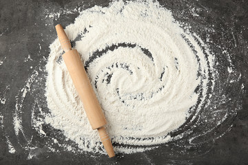 Scattered flour and rolling pin on grey table