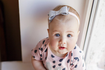  Portrait of cute baby girl with blue eyes near the window. Nursing and education for little children