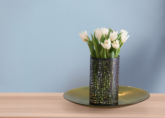 Vase with bouquet of tulips on wooden table in living room