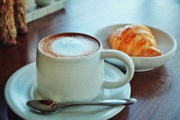 Coffee cup hot and croissant in the morning on wooden table