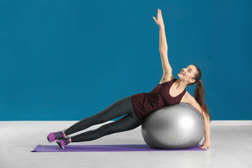 Beautiful young woman doing fitness exercise with ball at home