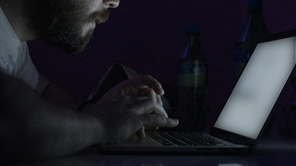The young handsome man learn in his computer at night. Man using the laptop in room at night
