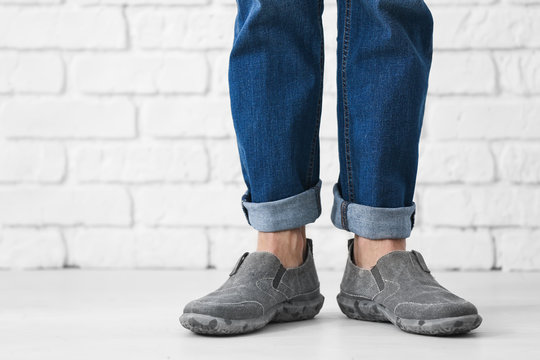 Man in casual shoes near brick wall