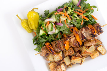 pork kebab skewer dish with potatoes and salad