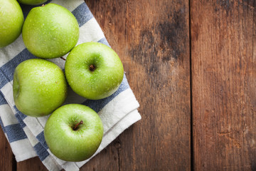 Ripe green apples in a wooden bowl on an old rustic table. Useful fruits on wooden background. Top view with copy space
