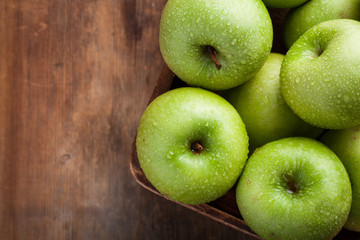 Ripe green apples in a wooden bowl on an old rustic table. Useful fruits on wooden background. Top view with copy space
