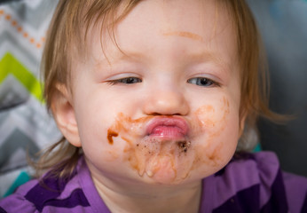 Toddler sticking out lips after eating chocolate 