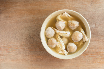 top view of meatballs soup with bean curd in a ceramic bowl on wooden table. homemade style healthy food concept.