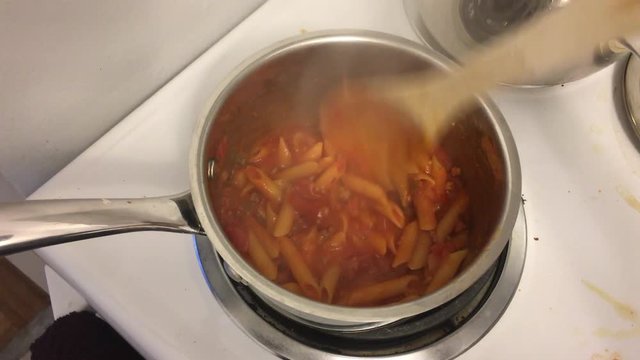 Mixing Penne Pasta with Wooden Spoon
