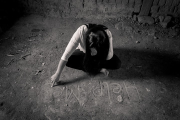 Give me support. Poor depressed woman folding her legs and sitting on the floor while writing help me