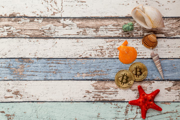 Two golden bitcoins with seashells and starfish on vintage wooden table top view